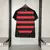 Camisa feminina do Flamengo 25/26, com listras vermelhas e pretas, destacando o emblema do clube e o logo da Adidas, com urubu.