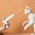 Um brinquedo interativo para gatos, na forma de uma pistola que dispara bolinhas, sendo utilizado por uma pessoa enquanto um gato brinca.