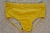 Yellow classic swim trunks for men displayed on sandy surface