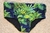 Men's Reserva Classic Swim Trunks featuring a tropical leaf pattern on a dark background.