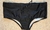 Black traditional workout trunks with a drawstring, laid flat on a sandy surface.