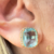 BRINCO COM PEDRA CENTRAL ACQUA CRAVEJADO DE ZIRCONIAS BANHADO A OURO 18k