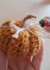 Cordão mágico de abóboras feito de crochê, em tons de laranja, com um cabo de papel e detalhes decorativos.