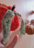 Cordão decorativo com abóboras feitas de lã e tecido, exibindo detalhes em verde e laranja.