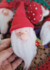 Gnominho Mágico com barba branca e chapéu vermelho, segurando um cogumelo, em um fundo colorido de outros gnomos.