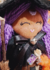 Boneca Bruxinha dos Cristais com cabelo roxo e vestido preto, segurando uma varinha e um frasco de cristais coloridos.