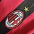 Detalhe do logo da Camisa Milan I Retro 09/10 Adidas, com cores vermelha e preta e estrela acima do emblema.
