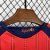 Kit infantil da seleção espanhola de futebol para Copa 2026, camisa vermelha com detalhes em amarelo e azul, e shorts azuis com o escudo da Espanha