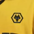 Camisa amarela do time Wolverhampton modelo 25/26 com gola preta e detalhes em preto, patrocinador DEBET na frente