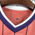 Camisa masculina rosa da seleção da Escócia para a Copa 2026, com listras verticais finas em azul, gola em V azul com detalhes brancos e logo Adidas branca no peito