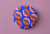 Merchandising de Infinito Café, pin naranja con diseño de trama de granos de café.