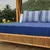 Jogo de lençol King em malha da marca Portallar. O lençol de baixo é na cor azul marinho liso e as fronhas são listradas em tons de azul claro e branco. A cama está disposta em um ambiente externo com decoração rústica de bambu. Envio de São Luís/MA para 