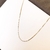 Colar veneziano em ouro 18k, com detalhes delicados e acabamento polido, sobre fundo branco.