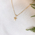 Colar em ouro 18K com pingente de menina adornado com zircônias, sobre fundo claro.