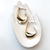 Brinco argola torcida em ouro 18k, com design moderno e elegante, apresentado sobre uma mão decorativa.