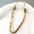 Pulseira essencial em ouro 18K, com design em fita, exposta sobre uma superfície clara.