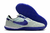 Chuteira Nike Streetgato Futsal cinza claro com detalhes em roxo e sola texturizada.