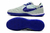 Chuteira Nike Streetgato Futsal cinza claro com detalhes em roxo e sola texturizada.