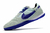 Chuteira Nike Streetgato Futsal cinza claro com detalhes em roxo e sola texturizada.