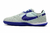 Chuteira Nike Streetgato Futsal cinza claro com detalhes em roxo e sola texturizada.