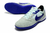 Chuteira Nike Streetgato Futsal cinza claro com detalhes em roxo e sola texturizada.