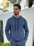 Homem usando um hoodie azul carbonado com capuz, em ambiente externo.