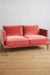 Sillón de dos cuerpos Philippe en color rosa suave, con almohadones cómodos y patas metálicas, sobre un suelo de madera.