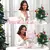 Mulher sorridente segurando o kit de spa Romantic Crown com produtos de beleza em uma mesa decorada para o Natal.