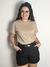 Camiseta básica gola careca bege com modelo usando óculos e brincos grandes.