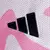 Detalhe do logo da Adidas em uma camisa de futebol com estampa rosa.
