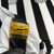 Detalhe da etiqueta da camisa do Santos Futebol Clube, com informações sobre o estádio Urbano Caldeira e a frase "A Vila Mais Famosa do Mundo".