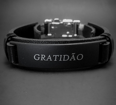 Pulseira premium preta com a inscrição "GRATIDÃO" em destaque.
