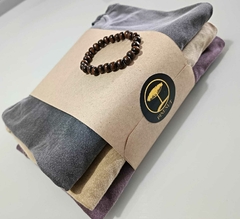 Conjunto de três camisetas da marca Pinenut embrulhadas com um cordão de contas em madeira e etiqueta da marca.