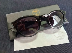 Óculos de sol unissex GRADE na cor preta, com lentes escuras, sobre uma superfície, ao lado de um estojo e um pano de limpeza.