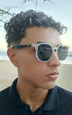 Jovem usando óculos de sol hexagonais PARIS em uma praia.
