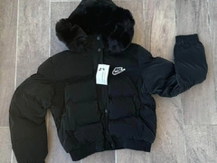 Campera puffer negra con capucha, de marca Nike, con detalles de pelaje en el borde y etiqueta colgante.