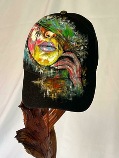 Gorra con diseño artístico que muestra un rostro colorido, parte de la colección de accesorios exclusivos de Misticas&amp;Urbanas.