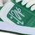 Imagem de um par de tênis Qix Chorão Lado B nas cores verde e branco, com detalhes em suede e cadarços brancos.