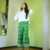 Modelo usando uma camisa branca de linho com calças verdes estampadas.