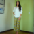 Modelo usando calça estampada com flores verdes e blusa branca em ambiente interno.
