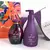 Kit Seve com desodorante hidratante corporal e óleo corporal de amêndoas e flor de ameixa, embalagens em tons de roxo e uma sacola colorida ao fundo.