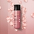 Frasco de body splash Nativa SPA Rosé com pétalas de rosa ao fundo.