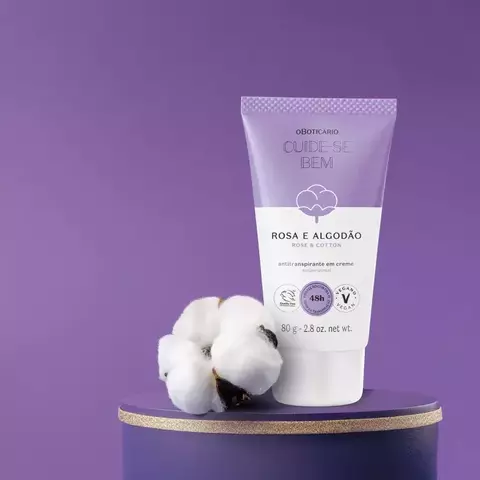 Embalagem do Antitranspirante em Creme O Boticário Cuide-se Bem Rosa e Algodão, com algodão ao lado, em fundo roxo.