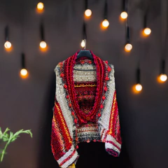 Jaqueta Casulo em tricô com design artesanal, feita com fios coloridos em tons de vermelho, branco, preto e detalhes em amarelo.