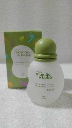 Frasco de 100 ml da água de colônia Mamãe e Bebê da Natura, com tampa verde e embalagem colorida ao fundo.