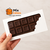 Caixa branca para barra de chocolate gourmet de 300g, com design elegante e chocolate visível através da embalagem.