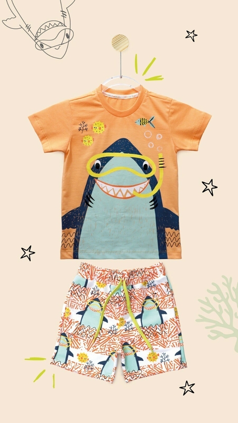 Conjunto infantil com camiseta laranja estampada com tubarão sorridente usando máscara de mergulho e bermuda branca estampada com vários tubarões e elementos marinhos.
