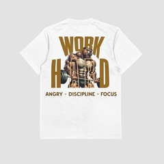 Camisa branca da Style fusion com estampa de um urso musculoso e texto "WORK HARD" em destaque, com as palavras "ANGRY - DISCIPLINE - FOCUS" abaixo.