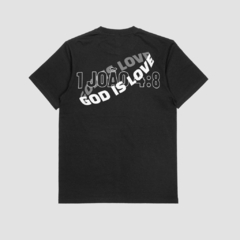 Camisa preta da Style fusion com a frase "God is Love" e a referência bíblica "1 João 4:8" estampadas na parte de trás.