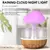 Umidificador de ar em formato de cogumelo com luzes coloridas e base de madeira, liberando névoa e gotas simuladas de chuva